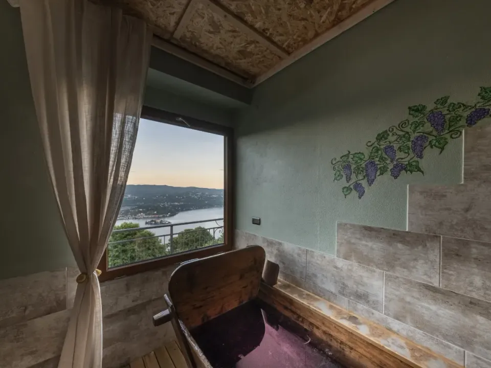 La tinozza in legno del Bagno di Bacco davanti alla finestra sul Lago d'Orta, con grappoli d'uva dipinti sulla parete
