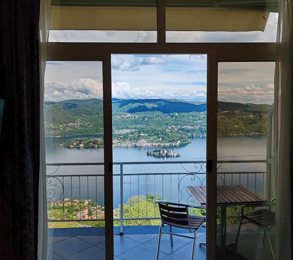 Vista sul Lago d'Orta e sull'Isola di San Giulio dalla porta-finestra della camera, con tavolino e sedie sul balcone