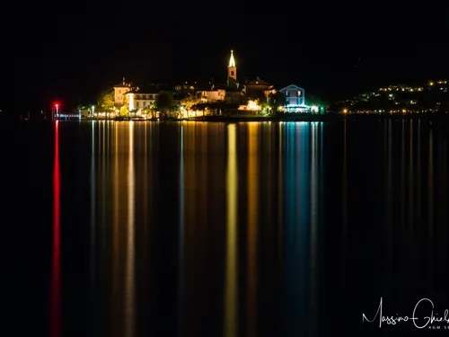 Isola dei Pescatori sul Lago Maggiore vista di notte, con le luci riflesse sull'acqua