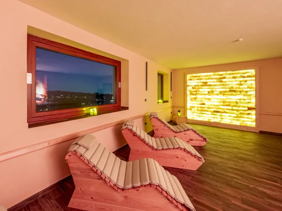 Sala del silenzio con lettini in legno e parete di sale rosa dell'Himalaya retroilluminata