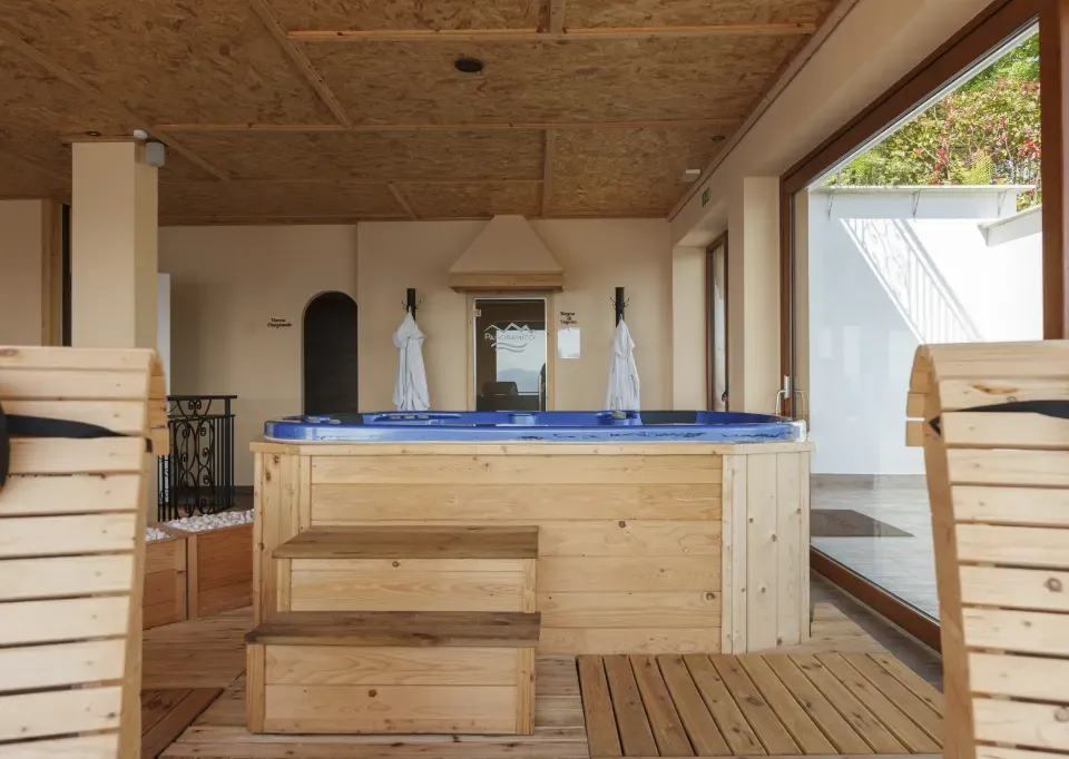 Vasca idromassaggio rivestita in legno della Kairos SPA, con accappatoi appesi e lettini in legno