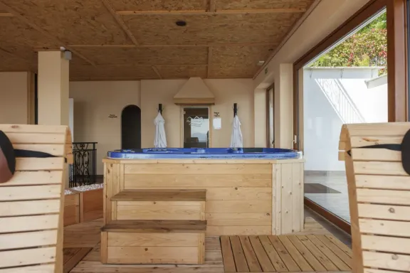 Vasca idromassaggio rivestita in legno della Kairos SPA, con accappatoi e lettini in legno